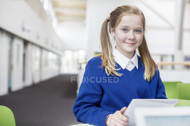 Портрет улыбающейся школьницы с блондинистыми косичками, держащей цифровой планшет — стоковое фото