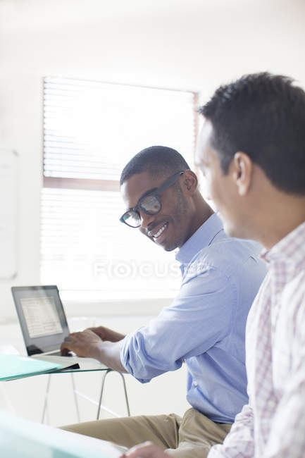 Empresarios trabajando con laptop en oficina moderna - foto de stock