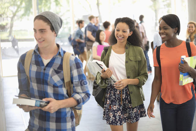University students carrying books and walking to classroom — Stock Photo