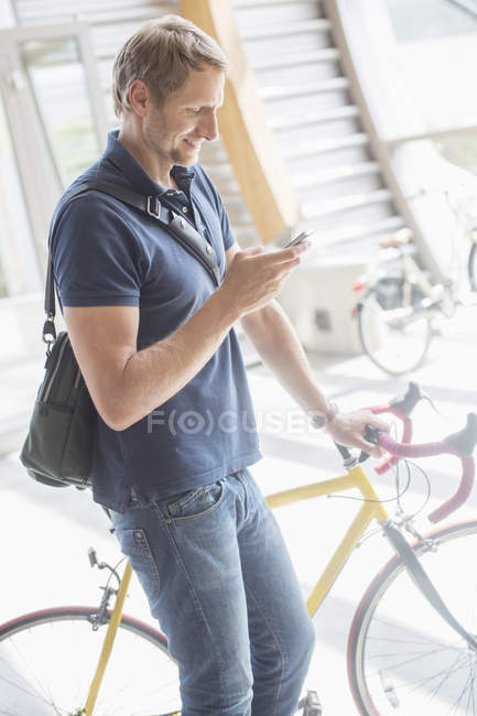 Mann benutzt Handy und hält Fahrrad — Stockfoto