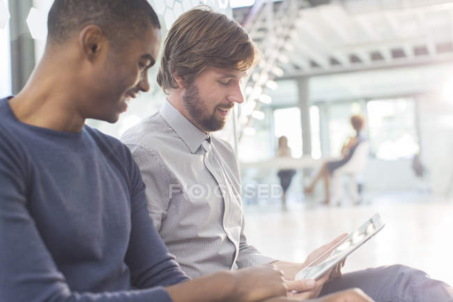 Two smiling businessmen using digital tablet in office — Stock Photo