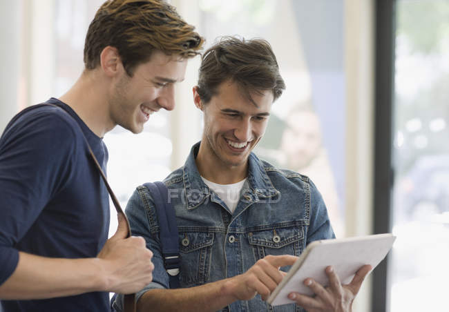 Двоє студентів чоловічої статі дивляться на цифровий планшет і сміються — стокове фото