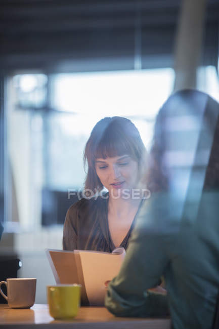 Empresárias lendo papelada no escritório — Fotografia de Stock