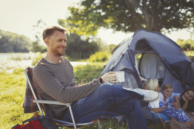 Sorrindo pai bebendo café fora da tenda no acampamento — Fotografia de Stock