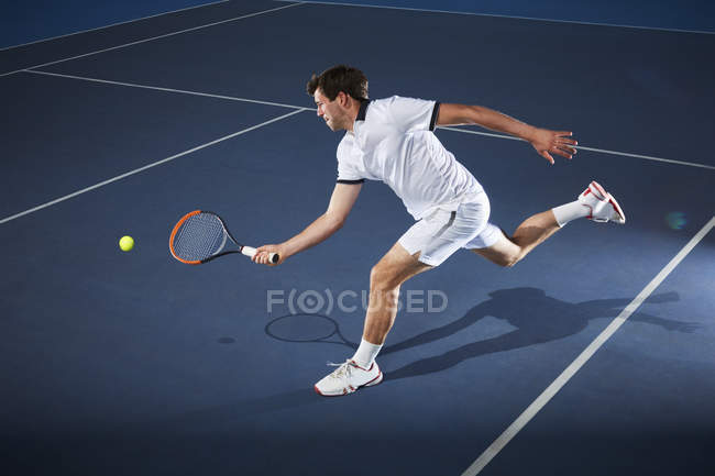 Male tennis player playing tennis, reaching with tennis racket on tennis court — Stock Photo
