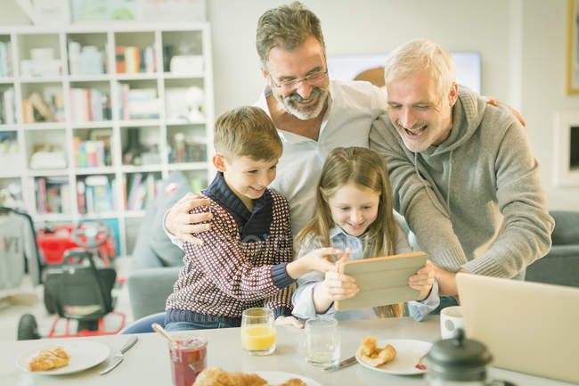 Masculino gay pais e crianças vídeo mensagens com digital tablet no manhã cozinha — Fotografia de Stock