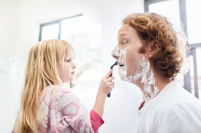 Daughter helping father shave face in bathroom — Stock Photo