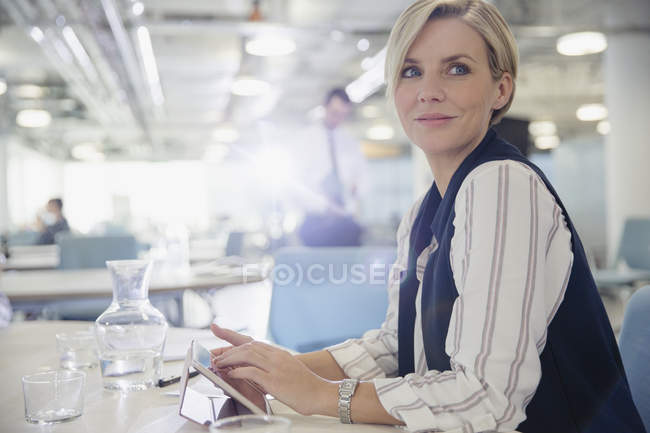 Усміхнена, впевнена бізнес-леді, використовуючи цифровий планшет на офісних зборах — стокове фото