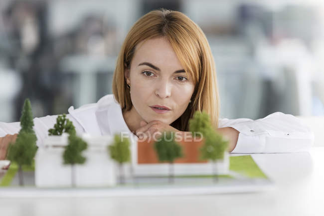 Ориентированная женщина-архитектор рассматривает модель — стоковое фото