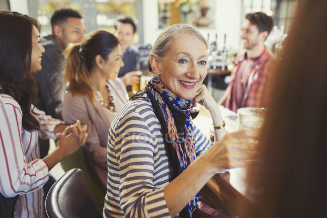 Lächelnde Seniorin trinkt und spricht mit Freundin an Bar — Stockfoto