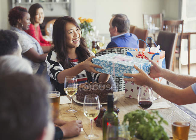 Smiling woman receiving birthday gift from friend at restaurant table — Stock Photo