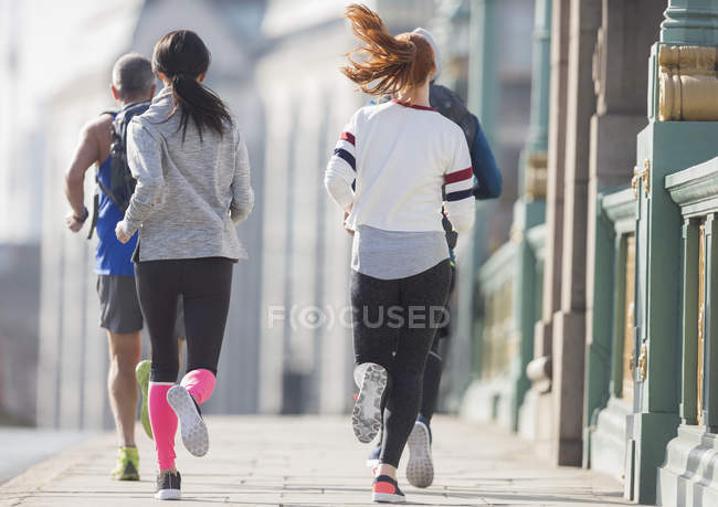 Runners running on sunny urban sidewalk — Stock Photo
