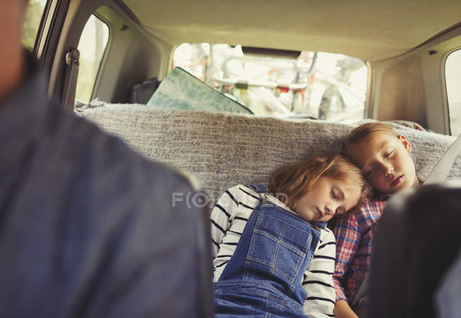 Втомлені сестри сплять на задньому сидінні автомобіля — стокове фото
