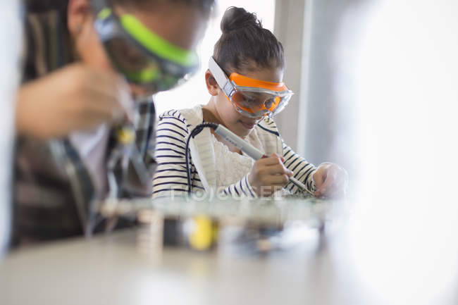 Focused girl students soldering circuit boards in classroom — Stock Photo