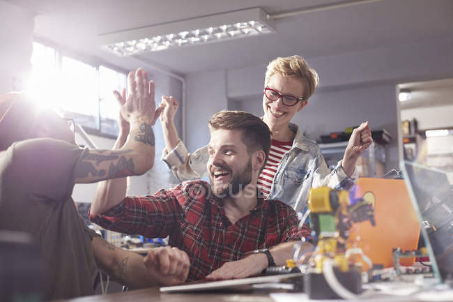 Enthusiastic designers high-fiving, celebrating in workshop — Stock Photo