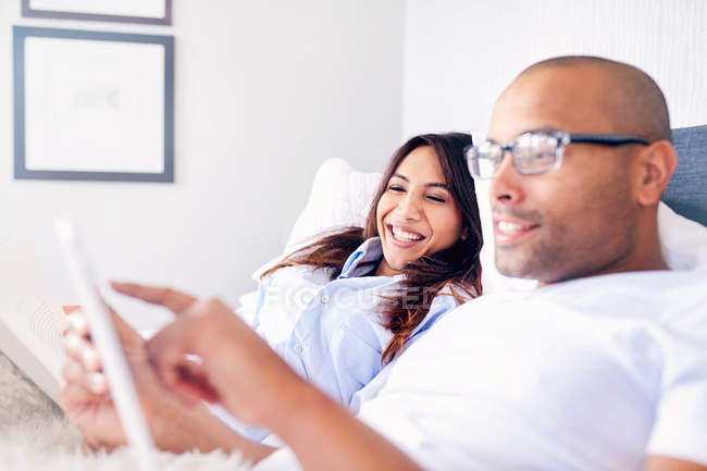Couple souriant utilisant une tablette numérique sur le lit — Photo de stock