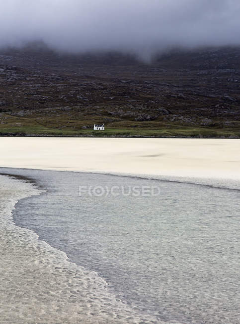 Tranquil view ocean and distant house, Luskentyre Beach, Harris, Ohmenrides — стоковое фото