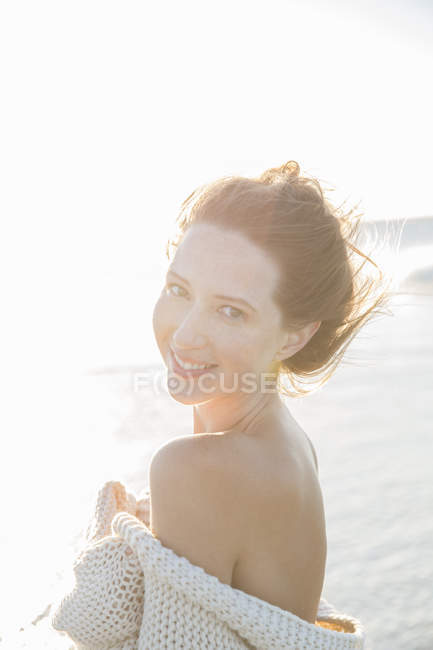 Portrait of young woman wrapped in blanket on beach — Stock Photo