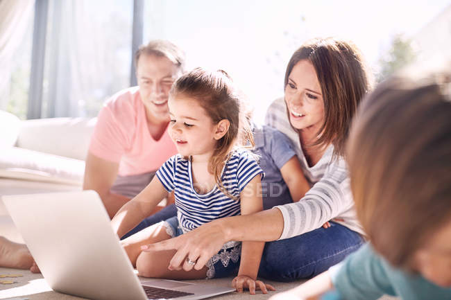 Familie nutzt Laptop im sonnigen Wohnzimmer — Stockfoto
