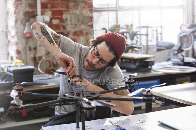 Designer maschio con tatuaggi assemblaggio drone in officina — Foto stock
