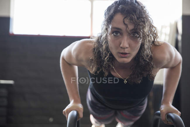 Portrait determined young woman doing push-ups with equipment in gym — Stock Photo