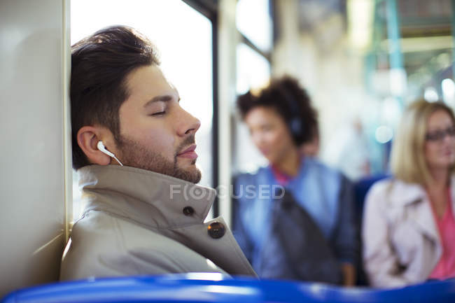 Empresario siesta y escucha auriculares en tren - foto de stock