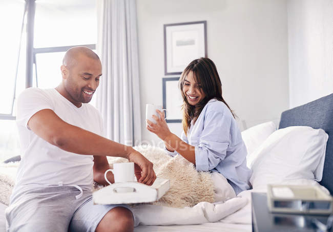 Sorridente coppia bere caffè a letto — Foto stock