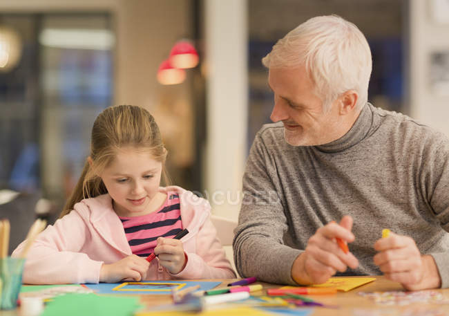 Отец и дочь сближаются, занимаются рукоделием за столом — стоковое фото