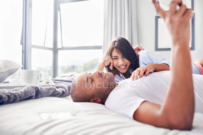 Smiling couple laying and relaxing on bed — Stock Photo