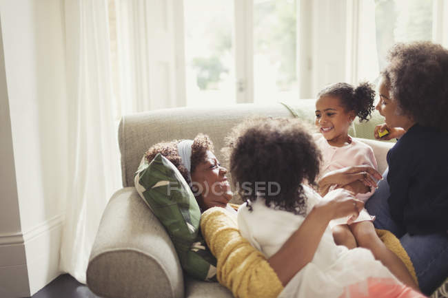 Affettuose figlie coccole madre sdraiata sul divano — Foto stock