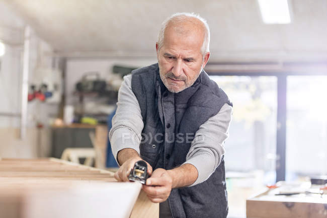 Focused senior male carpenter using jack plane on wood boat in workshop — Stock Photo