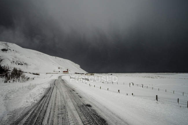 Road through snow covered landscape below stormy sky, Vik, Islândia — Fotografia de Stock