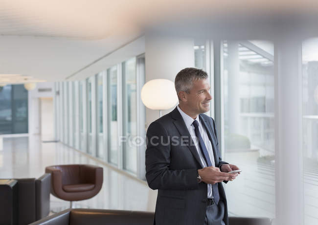 Businessman texting with cell phone in lounge — Stock Photo