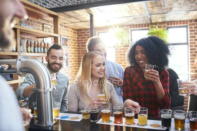 Amigos amostragem, beber cerveja no pub — Fotografia de Stock