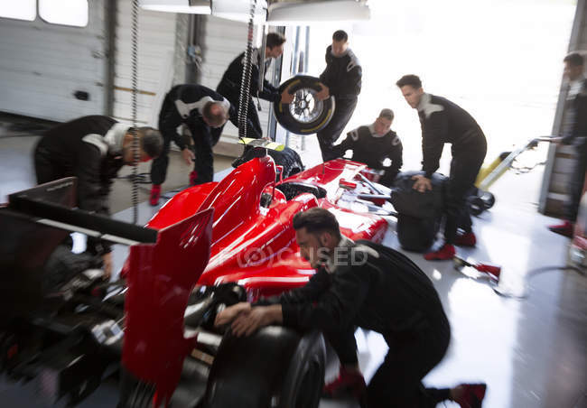 Екіпаж піт, який працює над формулою одного гоночного автомобіля в ремонтному гаражі — стокове фото