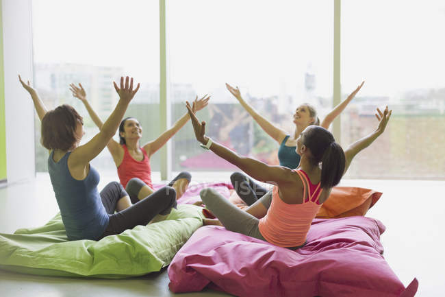 Mujeres apoyadas con los brazos levantados sobre cojines en el gimnasio de clase de ejercicio - foto de stock