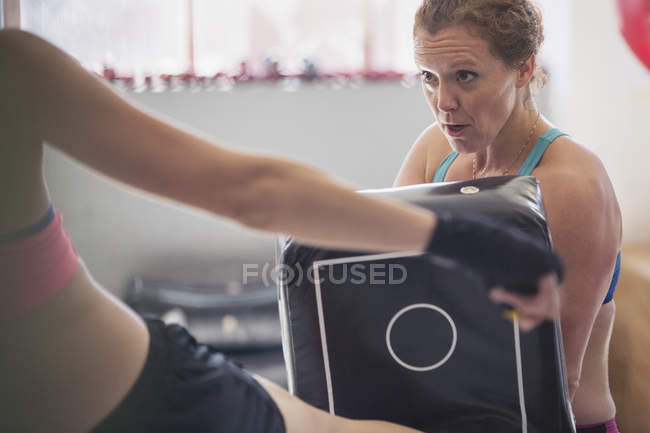 Mujeres determinadas kickboxing con almohadilla en el gimnasio - foto de stock