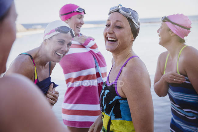 Улыбающиеся активные пловцы с полотенцами на открытом воздухе — стоковое фото