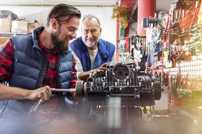 Male motorcycle mechanics repairing engine in workshop — Stock Photo