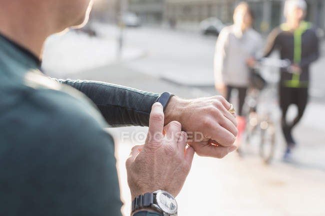 Male runner checking smart watch on urban sidewalk — Stock Photo