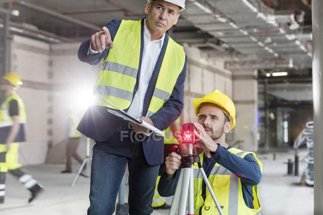 Hombre capataz e ingeniero con teodolito en obra - foto de stock