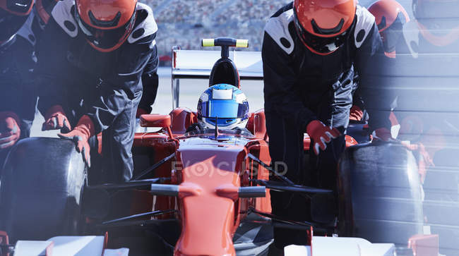 Equipage de stand remplaçant les pneus sur la formule 1 voiture de course dans pit lane — Photo de stock
