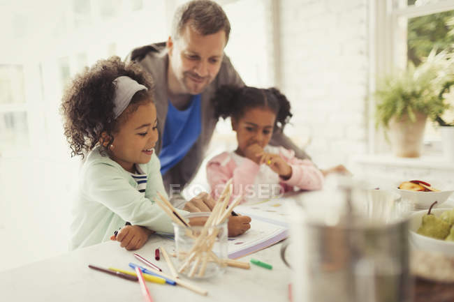 Multi-ethnic father and daughters coloring together — Stock Photo