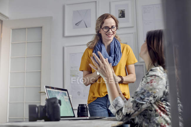 Женщины-фотографы разговаривают, встречаются в офисе — стоковое фото