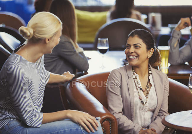 Lächelnde Freundinnen reden in Bar — Stockfoto