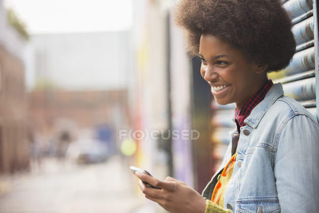 Vue latérale de femme noire heureuse en utilisant un smartphone — Photo de stock