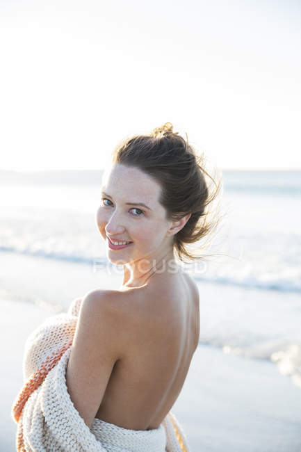 Portrait de jeune femme enveloppé dans une couverture sur la plage — Photo de stock