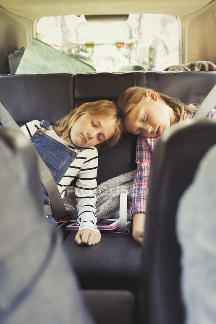 Hermanas cansadas durmiendo en el asiento trasero del coche - foto de stock