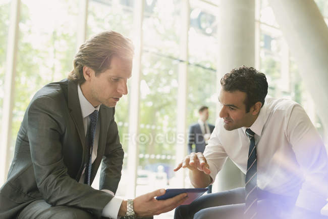 Réunion d'hommes d'affaires utilisant une tablette numérique dans le hall du bureau — Photo de stock