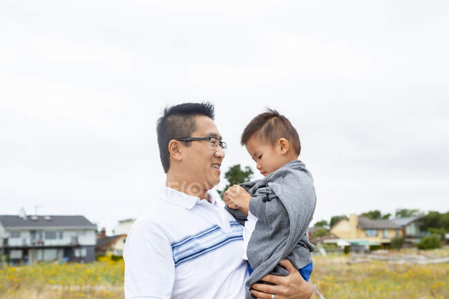 Chino padre holding hijo en parque - foto de stock